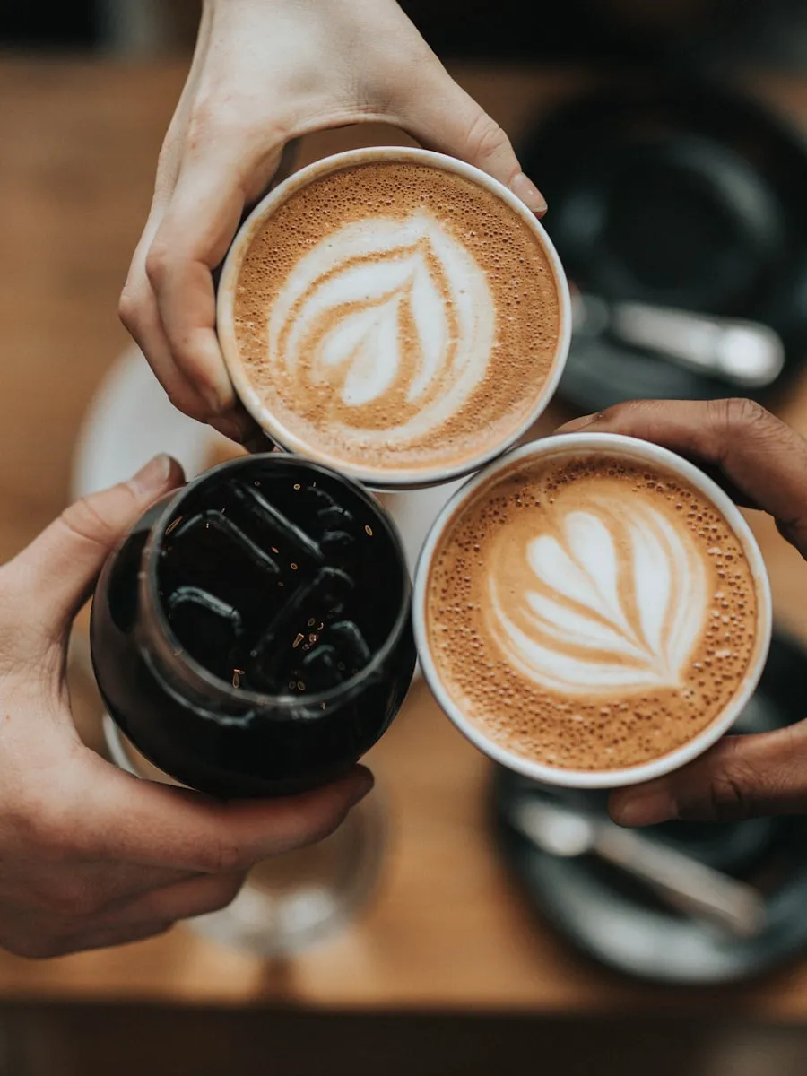 Three pairs of hands sharing coffee cups at a wooden table, a quiet ritual that stands in for the first morning of recovery